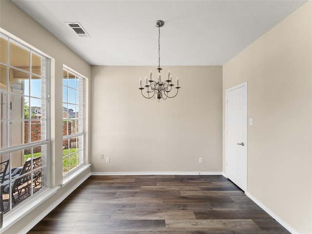 unfurnished dining area with baseboards, visible vents, a chandelier, and dark wood finished floors