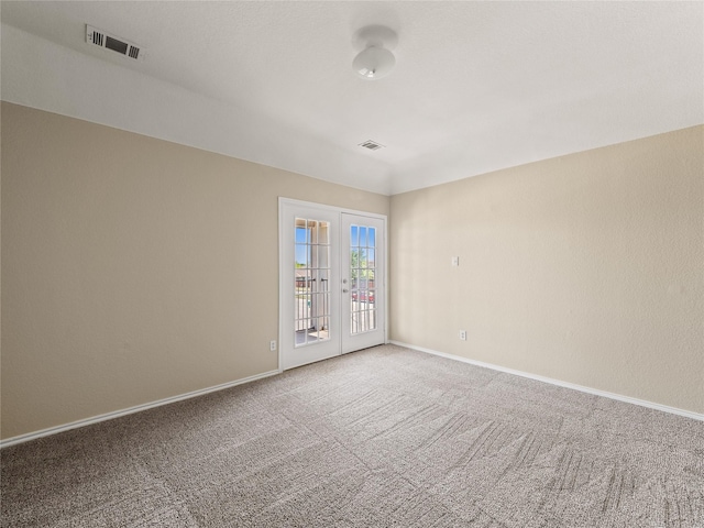 spare room featuring carpet floors, visible vents, baseboards, and french doors