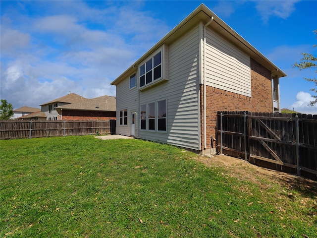 back of house with brick siding, a yard, a patio area, and a fenced backyard