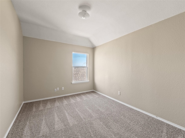 spare room with carpet floors, lofted ceiling, and baseboards