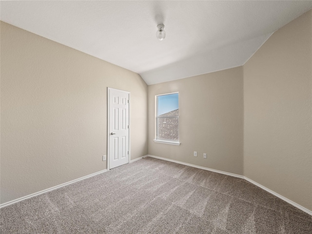 carpeted empty room with vaulted ceiling and baseboards