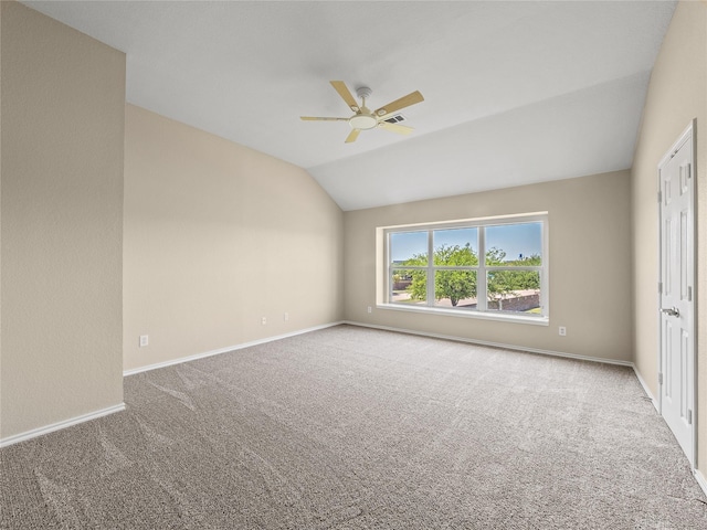empty room featuring carpet floors, a ceiling fan, vaulted ceiling, and baseboards