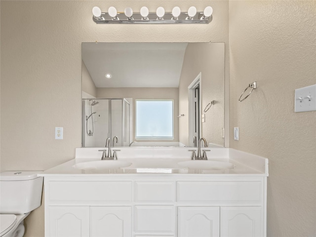 full bathroom featuring toilet, a sink, double vanity, and a stall shower