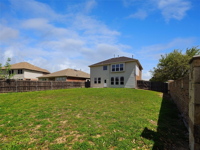 rear view of house featuring a fenced backyard and a yard