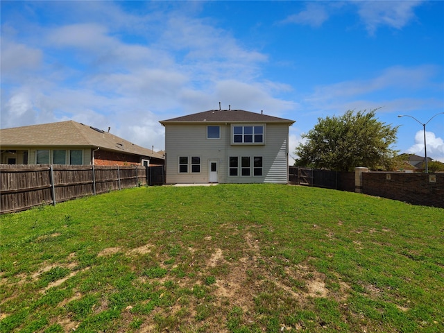 rear view of house with a yard and a fenced backyard
