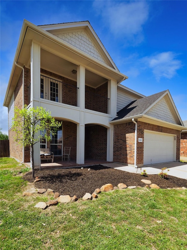 neoclassical home with a balcony, driveway, brick siding, a front yard, and a garage