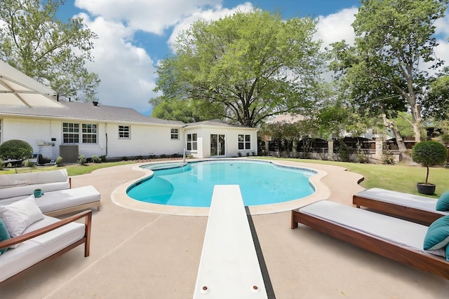 view of pool featuring a fenced in pool, an outbuilding, cooling unit, a patio area, and a diving board