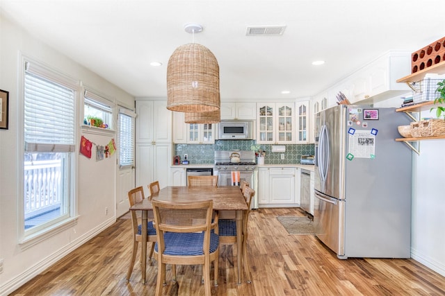kitchen featuring stainless steel appliances, visible vents, decorative backsplash, light wood-style flooring, and white cabinetry