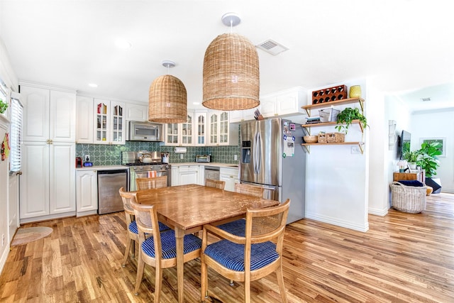 kitchen with backsplash, visible vents, light wood-style floors, appliances with stainless steel finishes, and white cabinetry