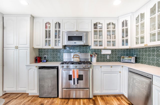kitchen with light countertops, white cabinetry, appliances with stainless steel finishes, and decorative backsplash