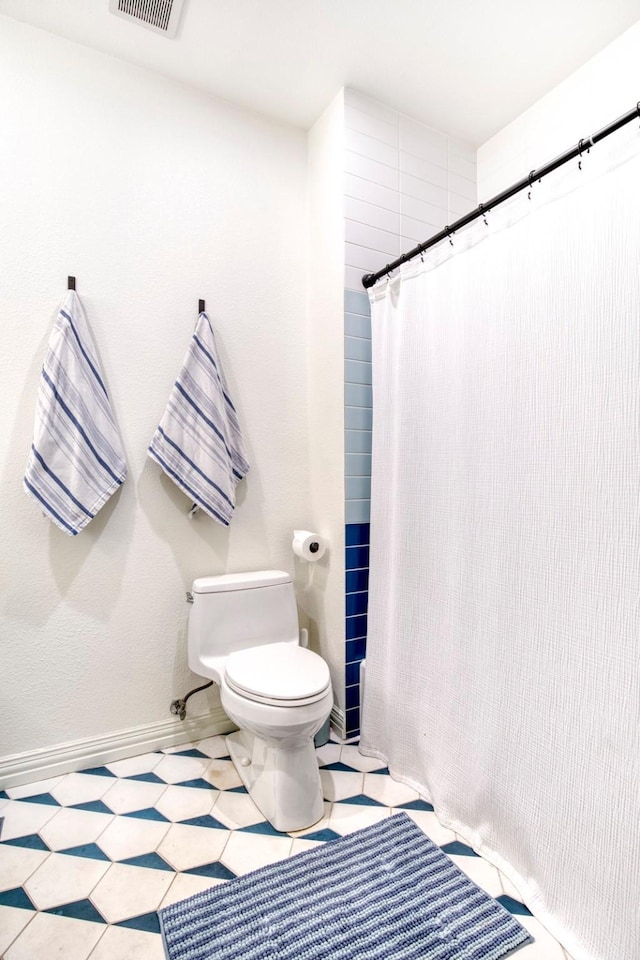 bathroom with toilet, a shower with shower curtain, and visible vents