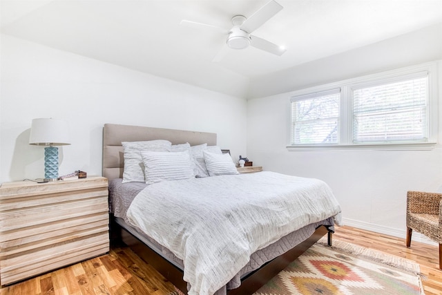 bedroom featuring ceiling fan, vaulted ceiling, wood finished floors, and baseboards