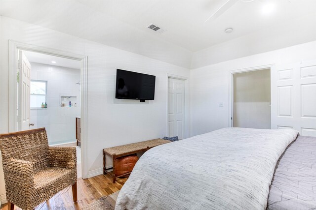 bedroom with ensuite bath, visible vents, and light wood finished floors