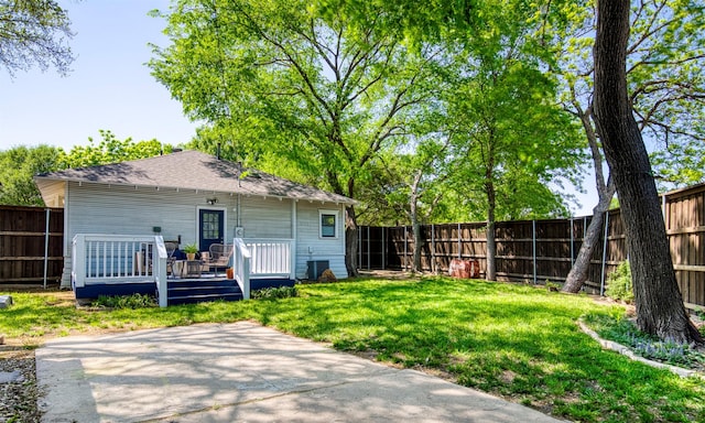rear view of property with roof with shingles, a fenced backyard, a wooden deck, a patio area, and a yard
