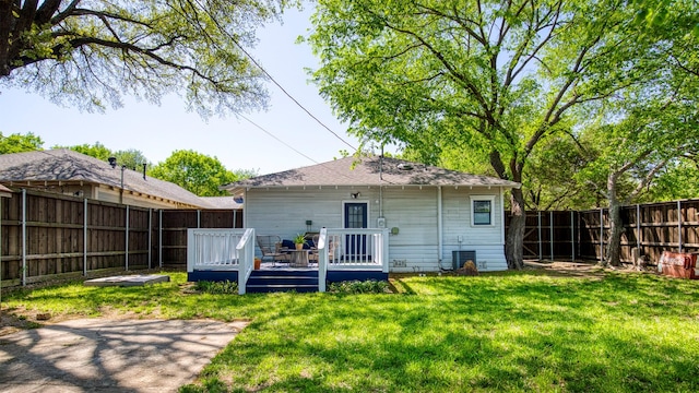rear view of property with a wooden deck, a fenced backyard, and a yard