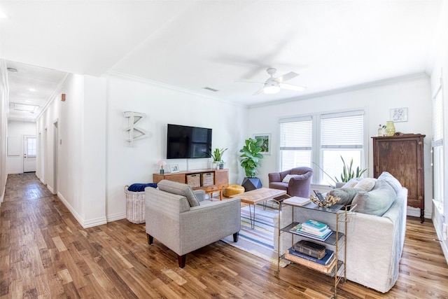 living room with wood finished floors, ornamental molding, and a healthy amount of sunlight