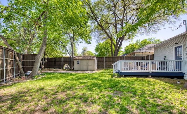 view of yard featuring a wooden deck, an outbuilding, a shed, and a fenced backyard