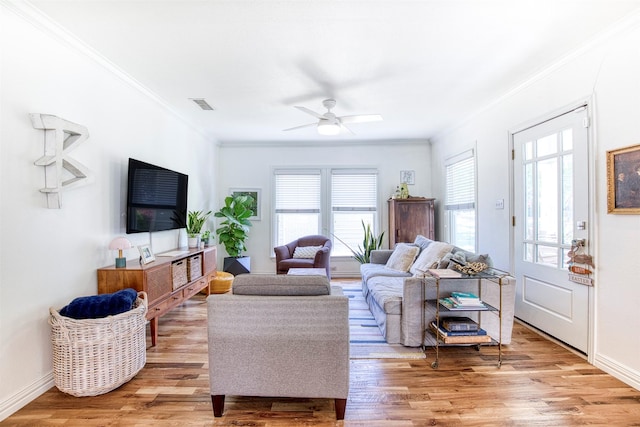 living room featuring light wood-type flooring, a ceiling fan, baseboards, and ornamental molding