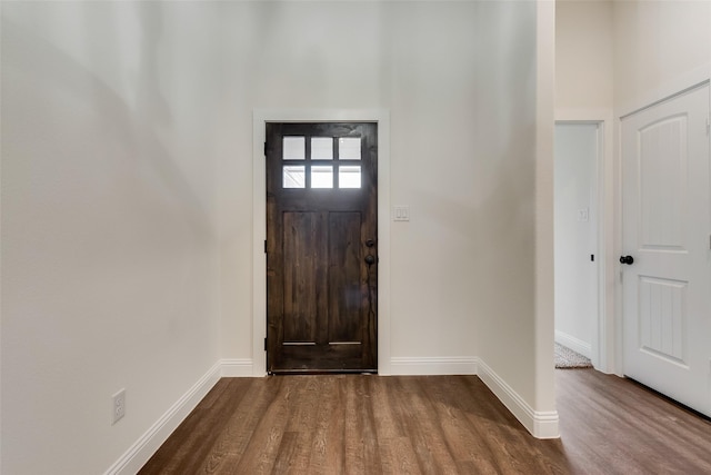 entryway featuring baseboards, dark wood-style floors, and a towering ceiling
