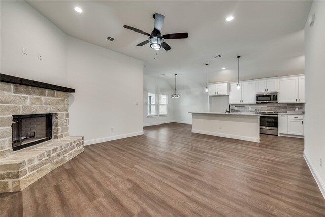 unfurnished living room featuring recessed lighting, a stone fireplace, wood finished floors, and ceiling fan