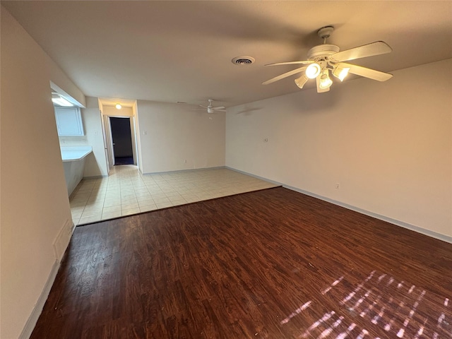 empty room with light wood-style flooring, visible vents, baseboards, and ceiling fan
