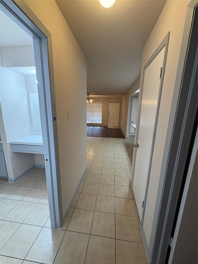 corridor with light tile patterned flooring and baseboards