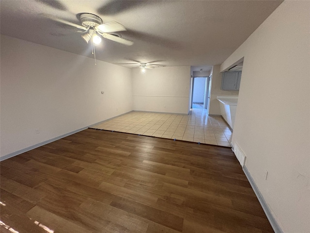 spare room with wood finished floors, visible vents, a ceiling fan, and baseboards