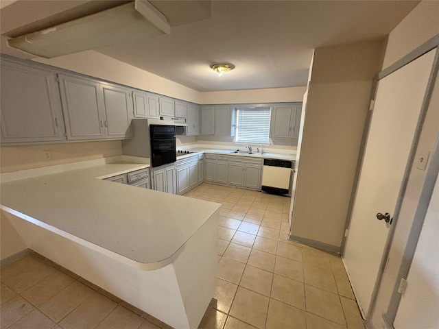kitchen featuring light countertops, a sink, white dishwasher, light tile patterned floors, and a peninsula