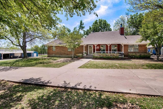 ranch-style house featuring brick siding, a front yard, a porch, and a chimney