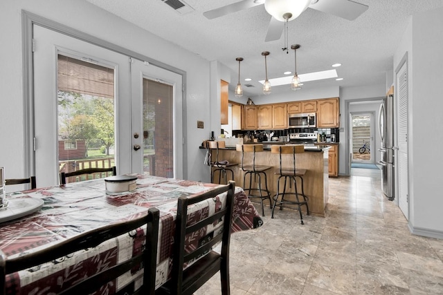 dining room featuring a textured ceiling, plenty of natural light, visible vents, and a ceiling fan