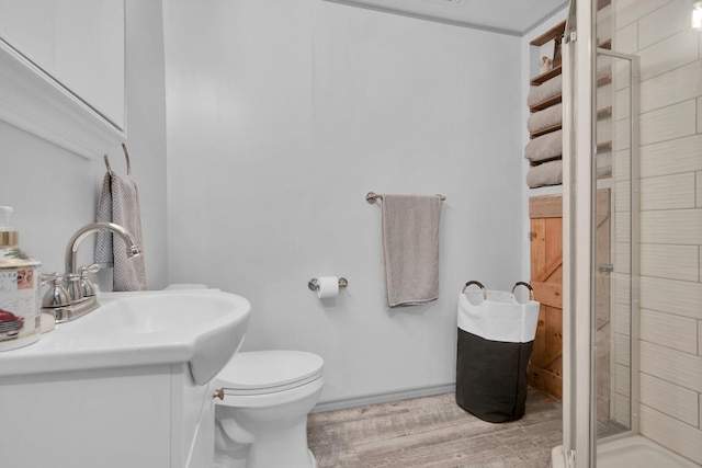 bathroom featuring toilet, wood finished floors, a stall shower, vanity, and baseboards