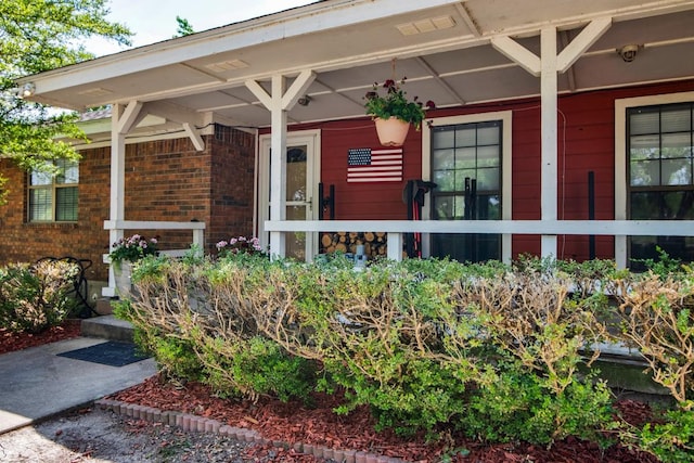 doorway to property with covered porch and brick siding