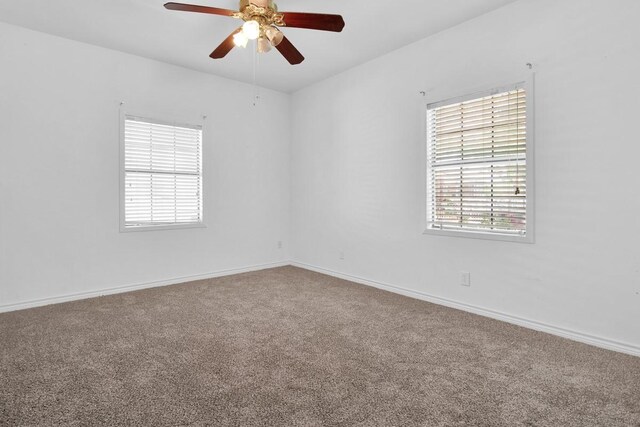 carpeted spare room with a ceiling fan and baseboards