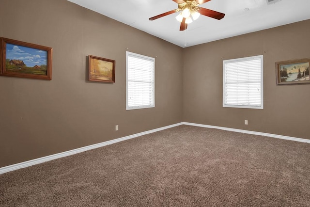 empty room with carpet floors, visible vents, a ceiling fan, and baseboards
