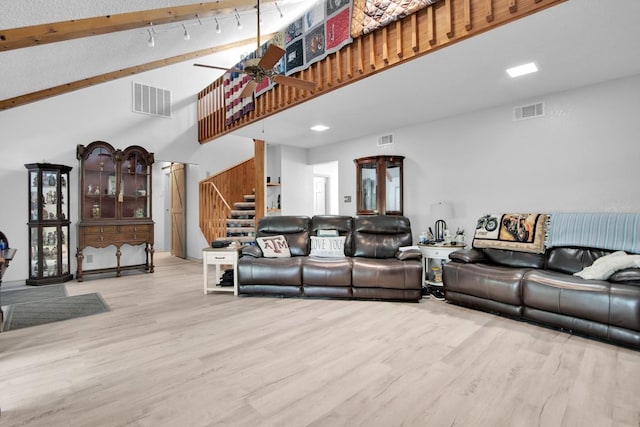 living area with wood finished floors, visible vents, a towering ceiling, and stairway