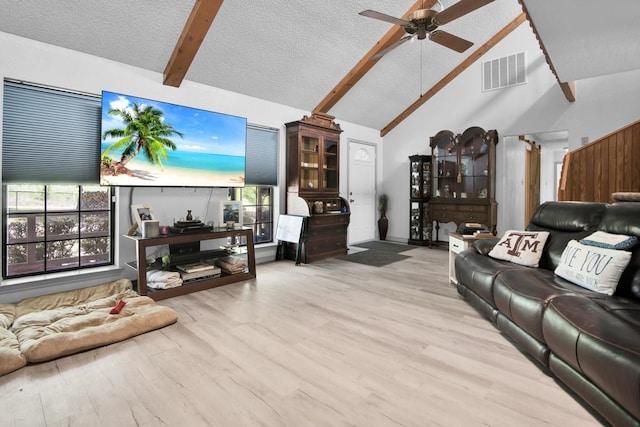 living area featuring ceiling fan, visible vents, wood finished floors, and beamed ceiling