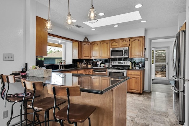 kitchen with stainless steel appliances, a kitchen breakfast bar, a sink, backsplash, and a skylight