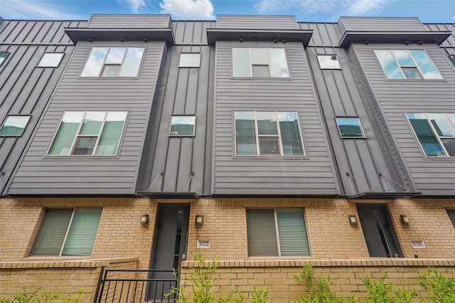 townhome / multi-family property with board and batten siding, brick siding, and fence