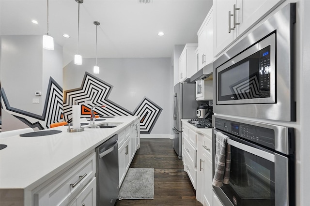 kitchen with stainless steel appliances, dark wood finished floors, white cabinetry, light countertops, and hanging light fixtures