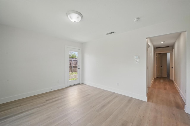 spare room with baseboards, light wood-style floors, and visible vents