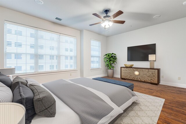 bedroom with a ceiling fan, baseboards, visible vents, and wood finished floors