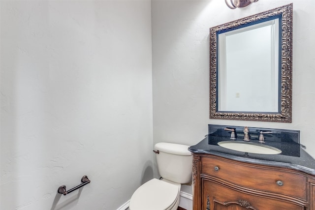 half bathroom with toilet, baseboards, and vanity