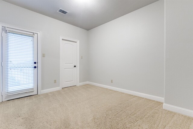 carpeted spare room featuring baseboards, plenty of natural light, and visible vents