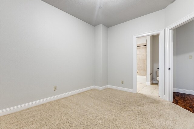 unfurnished bedroom with baseboards, carpet flooring, and ensuite bath