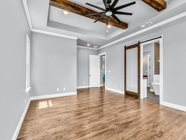 117 Fan Mill Trl, Weatherford, TX 76085 - unfurnished bedroom featuring a barn door, visible vents, recessed lighting, wood finished floors, and a raised ceiling