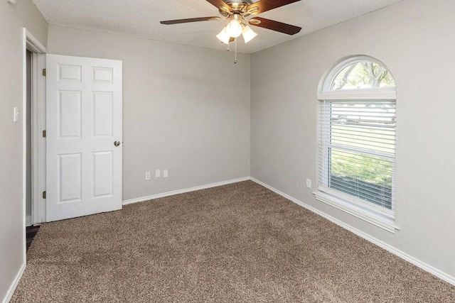spare room with a textured ceiling, carpet flooring, baseboards, and ceiling fan