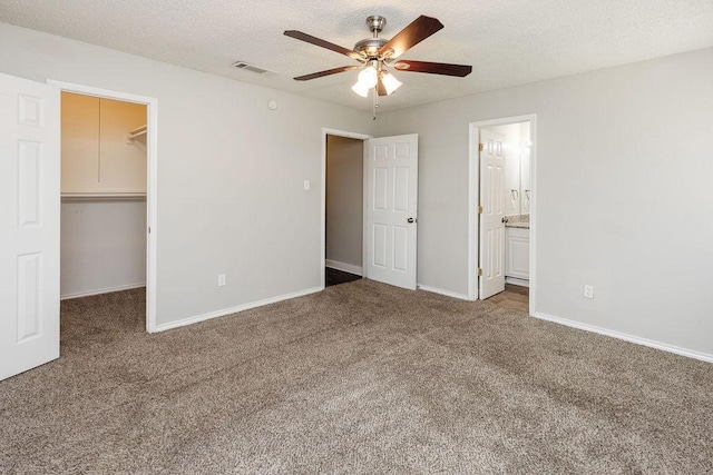 unfurnished bedroom featuring baseboards, a spacious closet, visible vents, a closet, and carpet floors