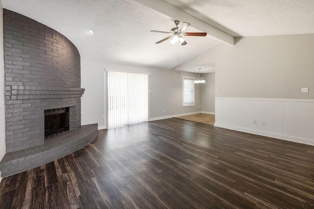 unfurnished living room featuring ceiling fan with notable chandelier, vaulted ceiling with beams, a fireplace, and a textured ceiling