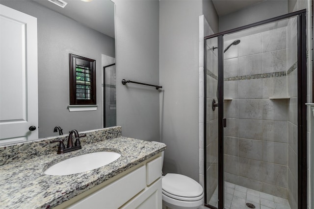 bathroom with a shower stall, toilet, and vanity