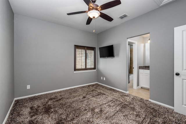 unfurnished bedroom with visible vents, ensuite bath, baseboards, light colored carpet, and ceiling fan